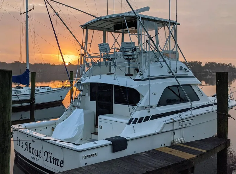 Slide: The Image of 1988 Bertram 37 Convertible yacht docked at sunset, featuring a spacious deck and flybridge. - 4