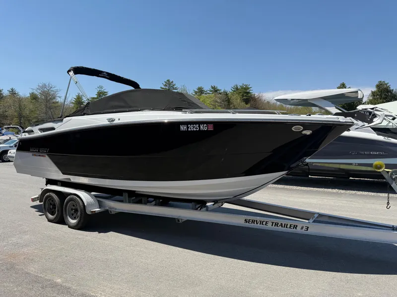 Slide: The Image of 2023 Monterey 258 Super Sport boat on trailer, black hull, parked outdoors. - 0