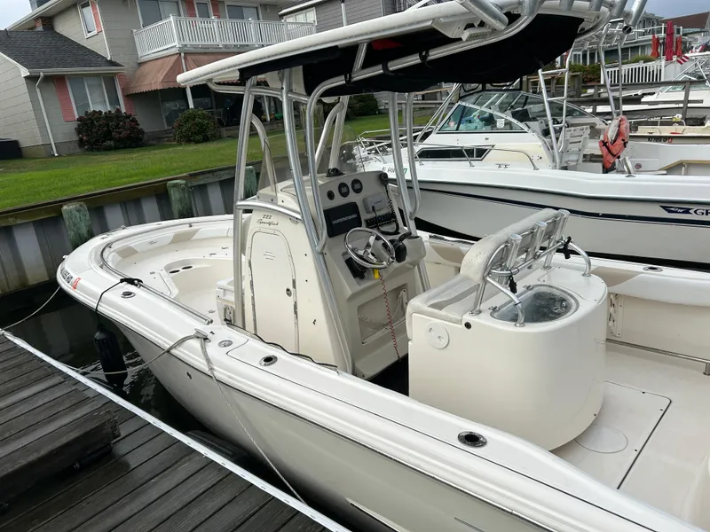 Slide: The Image of 2011 Pioneer 222 Sportfish boat docked, featuring center console and T-top. - 2