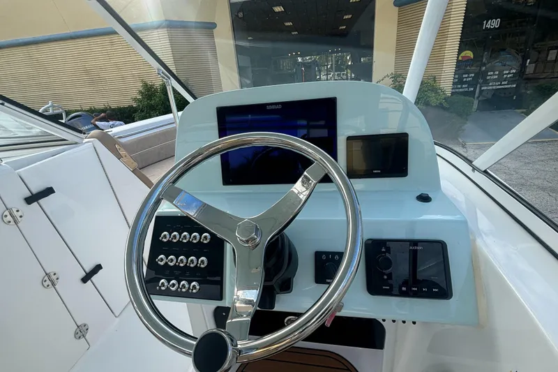 Slide: The Image of 2025 Sea Pro 240 Dual Console boat dashboard with steering wheel and electronic controls. - 11
