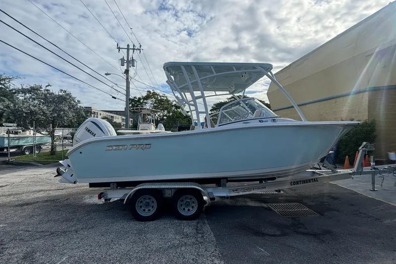Slide: The Image of 2025 Sea Pro 240 Dual Console boat on trailer, parked outdoors under cloudy sky. - 5