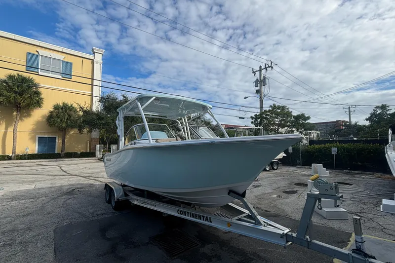 Slide: The Image of 2025 Sea Pro 240 Dual Console boat on trailer, parked outdoors under a cloudy sky. - 6