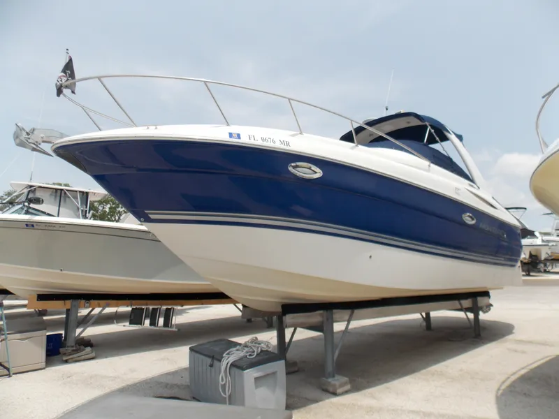 Slide: The Image of 2005 Monterey 270 Cruiser boat on display, blue and white hull, docked on land. - 2