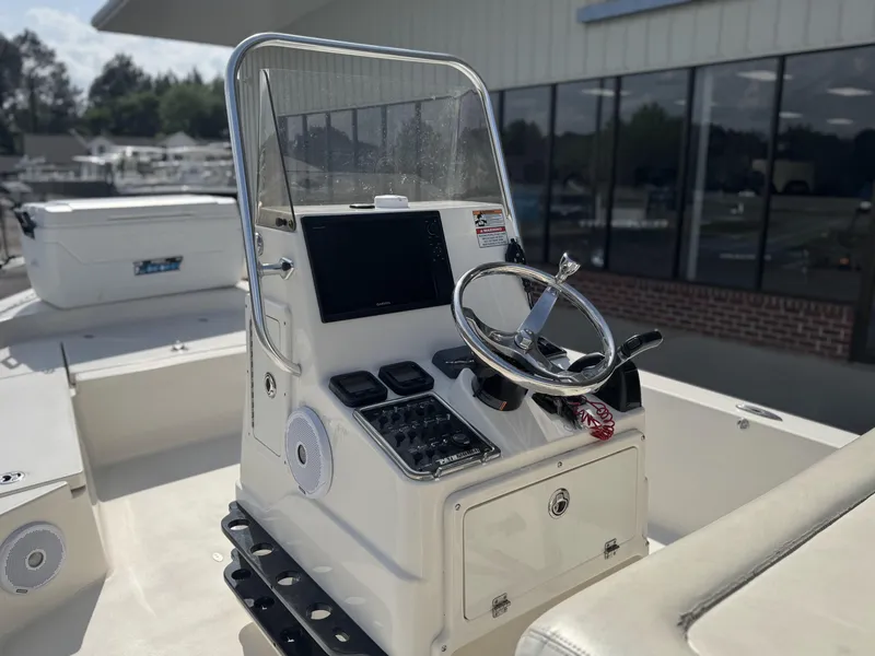 Slide: The Image of 2014 Pathfinder 2200 TRS boat console with steering wheel and controls, docked near a building. - 10