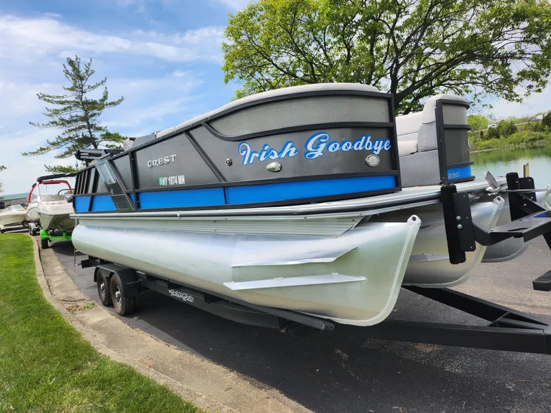 Slide: The Image of 2017 Crest Caliber 230 SLC pontoon boat named "Irish Goodbye" on a trailer by a lake. - 8
