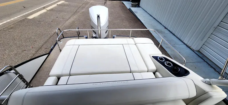 Slide: The Image of 2020 Bennington R 25 RSBA boat with white seating and cup holders, docked near a building. - 12