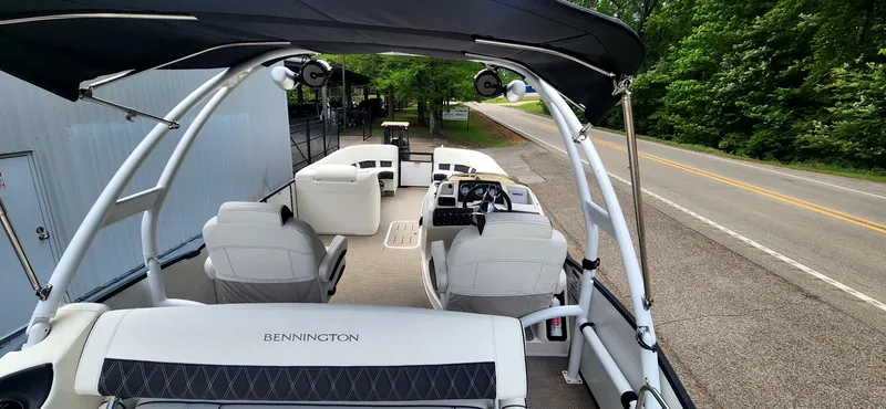 Slide: The Image of 2020 Bennington R 25 RSBA pontoon boat interior with seating and helm, parked roadside. - 14