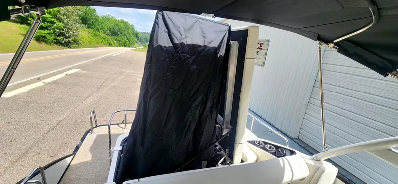 Slide: The Image of 2020 Bennington R 25 RSBA boat with covered console, parked near a road and building. - 15