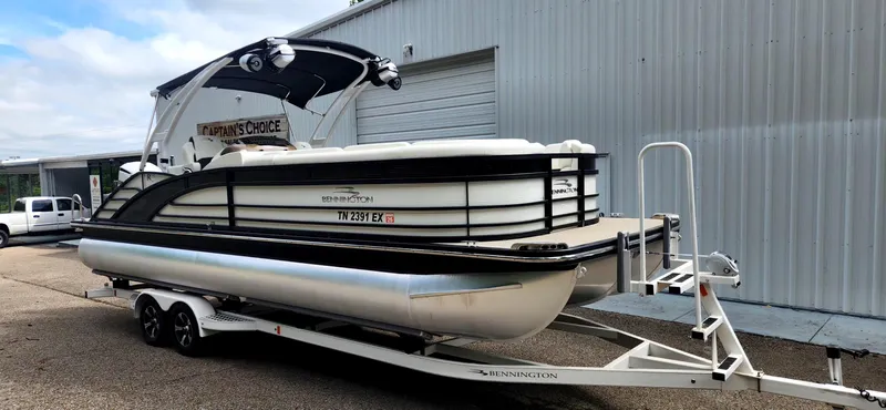 Slide: The Image of 2020 Bennington R 25 RSBA pontoon boat on trailer, parked beside a metal building. - 2
