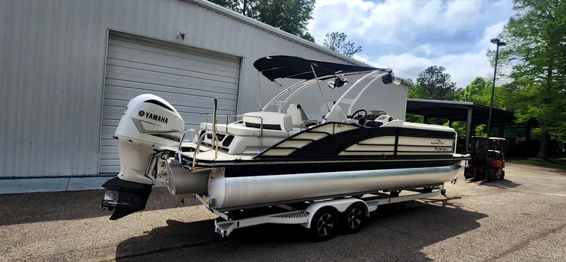 Slide: The Image of 2020 Bennington R 25 RSBA pontoon boat with Yamaha engine on trailer, parked outside a warehouse. - 3