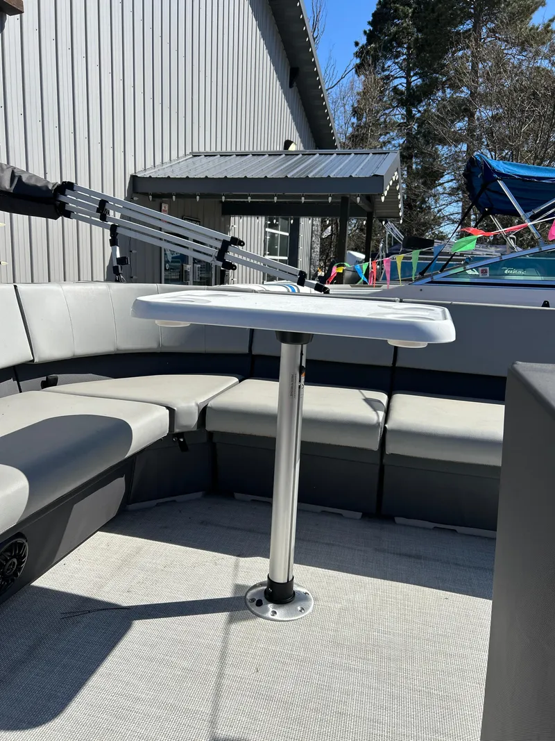 Slide: The Image of 2025 Custom Maui 210 Cruise boat interior with seating and table, docked outdoors. - 11