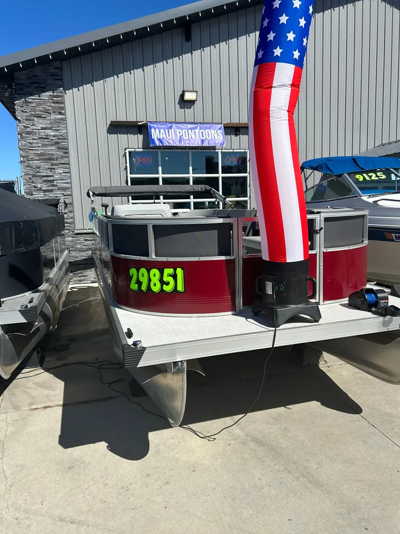 Slide: The Image of 2025 Custom Maui 210 Cruise pontoon boat displayed at dealership with American flag decoration. - 7