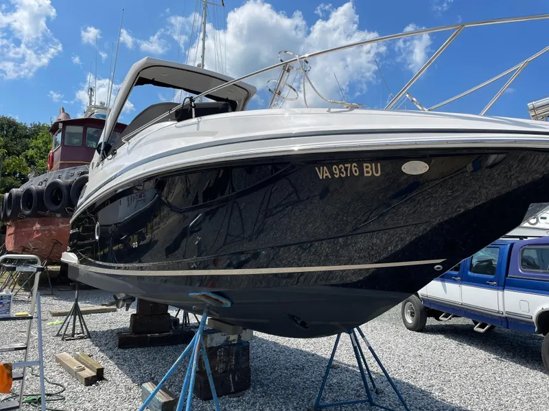 The Image of 2014 Regal 28 Express boat on stands, black hull, clear sky background. - 1