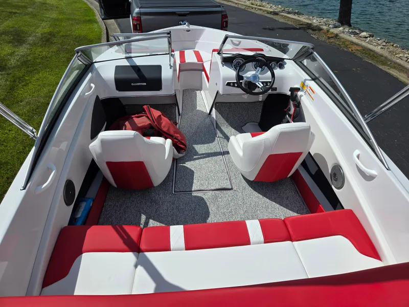 Slide: The Image of 2014 Glastron GT 185 boat interior with red and white seating, near water. - 10