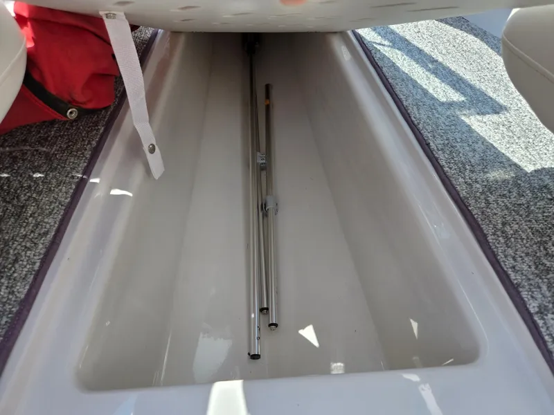 Slide: The Image of Storage compartment in a 2014 Glastron GT 185 boat, featuring carpeted interior and metal poles. - 12