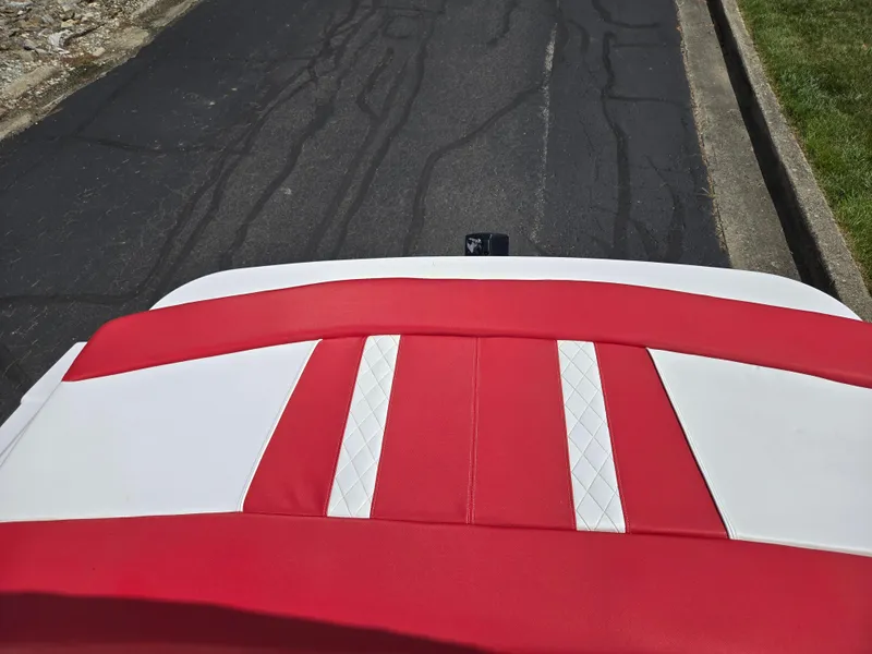 Slide: The Image of 2014 Glastron GT 185 boat with red and white upholstery, parked on asphalt. - 22