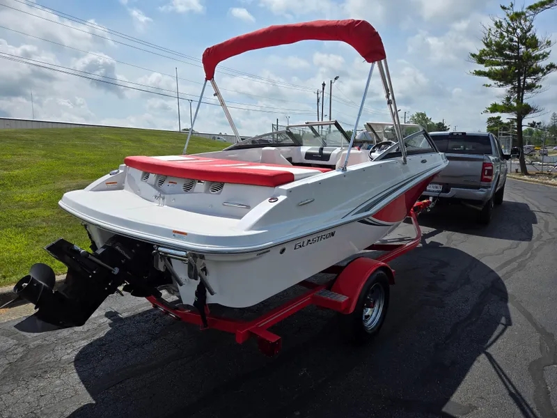Slide: The Image of 2014 Glastron GT 185 boat on trailer, red and white design, parked outdoors. - 3