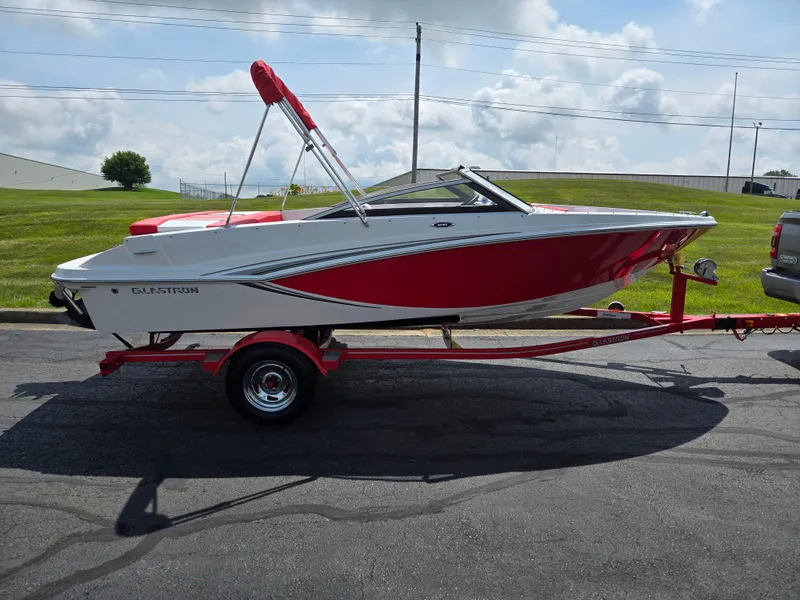Slide: The Image of 2014 Glastron GT 185 boat on trailer, red and white design, parked outdoors. - 4
