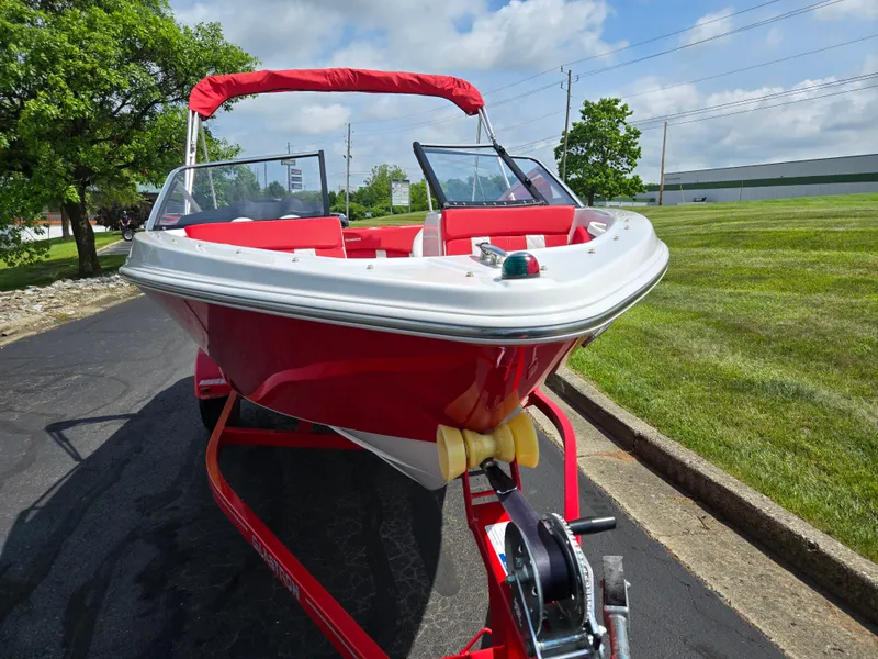 Slide: The Image of 2014 Glastron GT 185 boat with red and white design on a trailer, parked outdoors. - 6