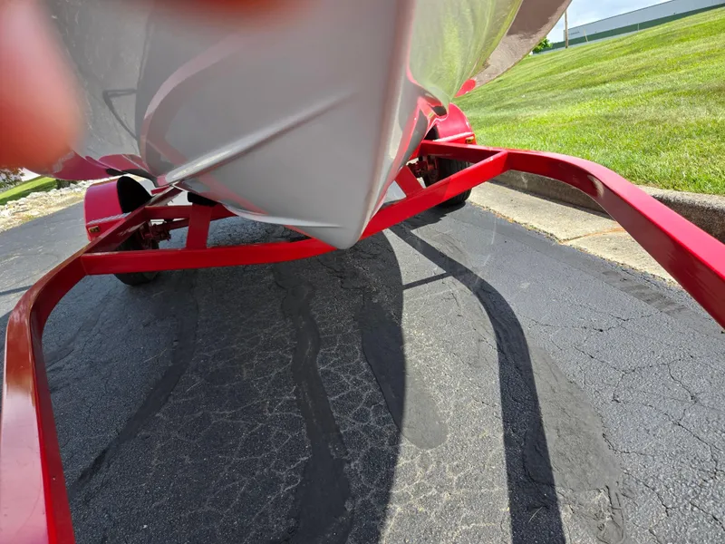 Slide: The Image of 2014 Glastron GT 185 boat on a red trailer, parked on asphalt. - 7