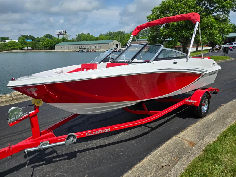 Slide: The Image of 2014 Glastron GT 185 boat in red and white on a matching trailer by a lake. - 8