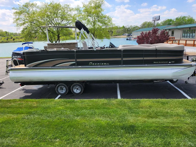 Slide: The Image of 2013 Premier 290 Grand Entertainer pontoon boat on trailer, parked near a lake. - 11
