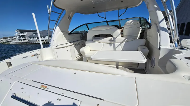 Slide: The Image of 2003 Sea Ray 410 Express Cruiser interior with seating and table, docked near waterfront homes. - 10
