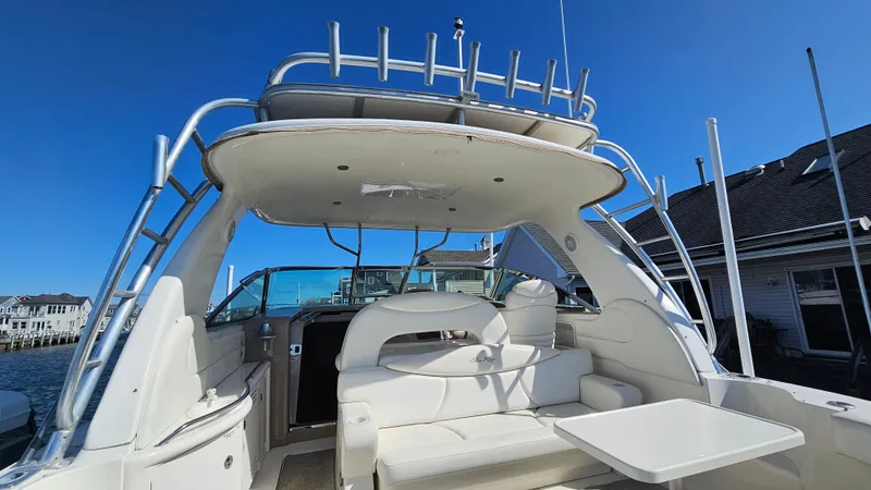 Slide: The Image of 2003 Sea Ray 410 Express Cruiser with spacious seating and table under clear blue sky. - 14
