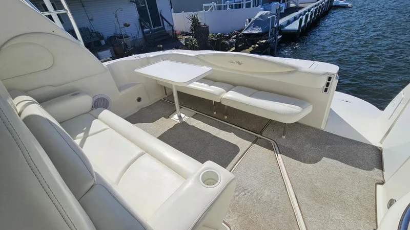 Slide: The Image of 2003 Sea Ray 410 Express Cruiser interior with white seating and table, dockside view. - 24