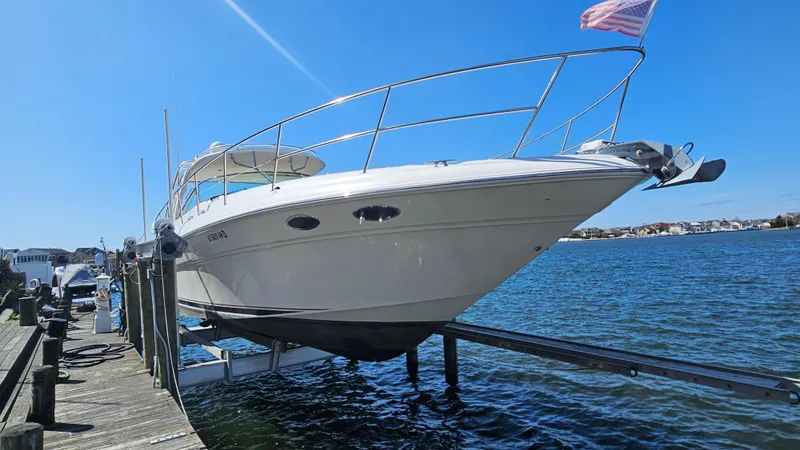 Slide: The Image of 2003 Sea Ray 410 Express Cruiser on lift by dock, clear blue sky. - 3