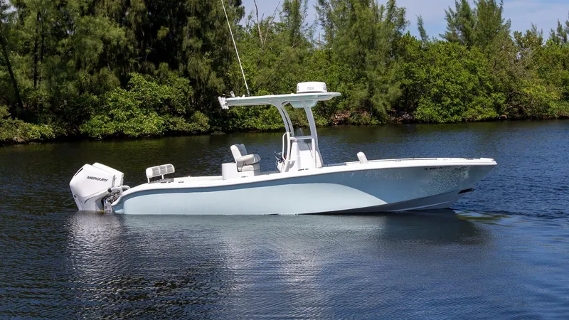 Slide: The Image of 2022 Yellowfin 26 Hybrid boat on calm water, surrounded by lush greenery. - 1
