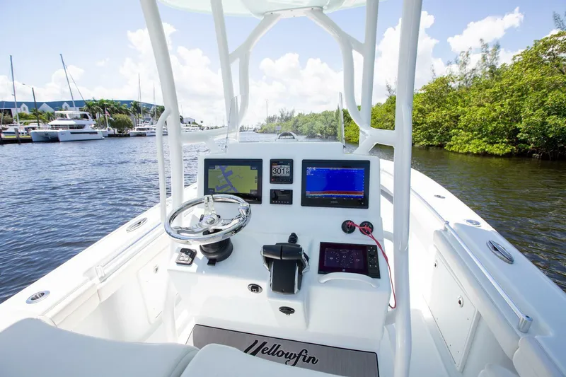 Slide: The Image of 2022 Yellowfin 26 Hybrid boat cockpit with modern navigation equipment, steering wheel, and lush surroundings. - 11