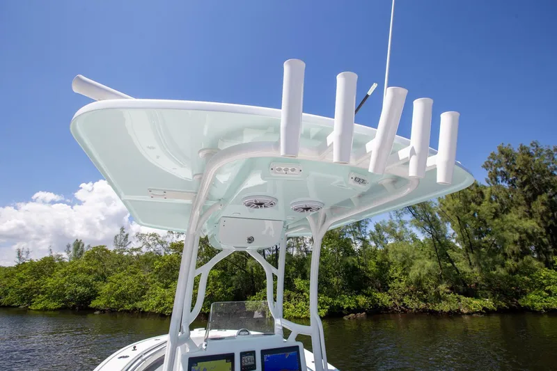 Slide: The Image of 2022 Yellowfin 26 Hybrid boat with rod holders, clear sky, and lush greenery background. - 14