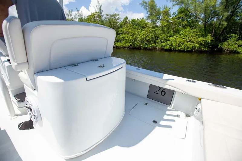 Slide: The Image of 2022 Yellowfin 26 Hybrid boat interior with seating and storage, near lush greenery. - 17