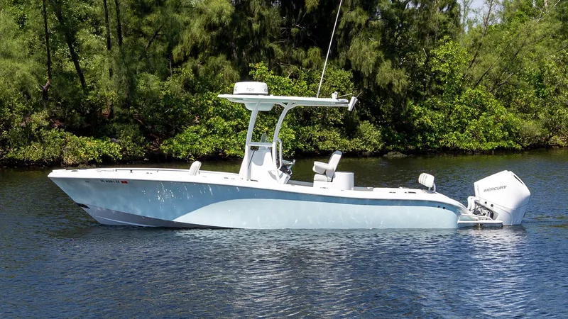 Slide: The Image of 2022 Yellowfin 26 Hybrid boat on calm water, surrounded by lush greenery. - 4