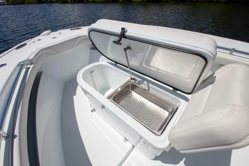 Slide: The Image of 2022 Yellowfin 26 Hybrid boat with open storage compartment near water. - 7