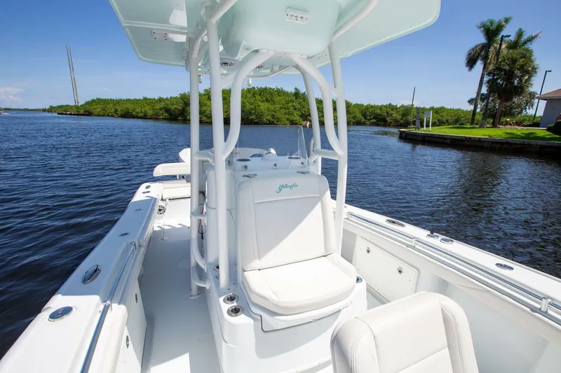Slide: The Image of 2022 Yellowfin 26 Hybrid boat on calm water, featuring sleek white seating and console. - 8