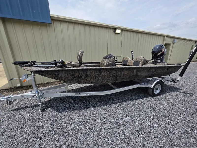 Slide: The Image of 2025 Xpress XP180 boat on trailer, parked on gravel near a metal building. - 1