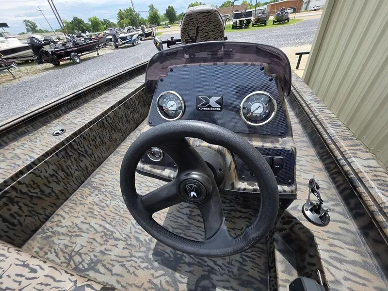 Slide: The Image of 2025 Xpress XP180 boat dashboard with camouflage design and steering wheel. - 19