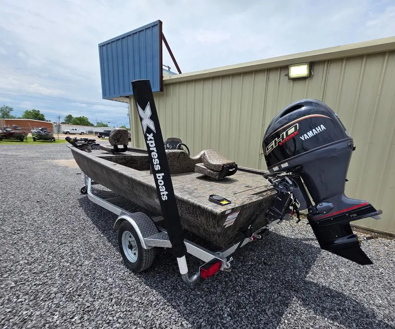Slide: The Image of 2025 Xpress XP180 boat with Yamaha motor on trailer, parked on gravel. - 23