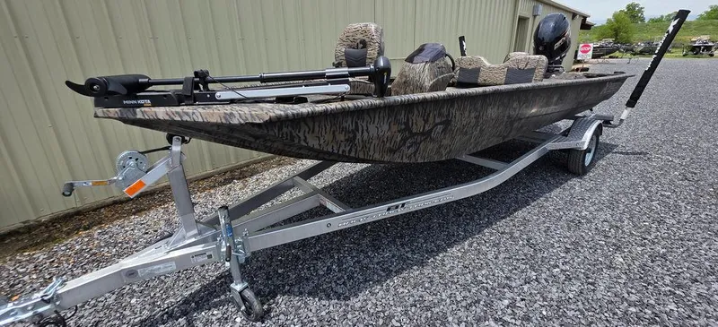 Slide: The Image of 2025 Xpress XP180 boat on trailer, camo design, parked on gravel near building. - 24