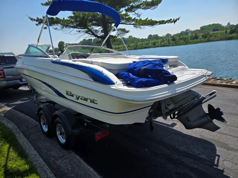 Slide: The Image of 2013 Bryant 210 STE boat on trailer by a lake, under a clear sky. - 1