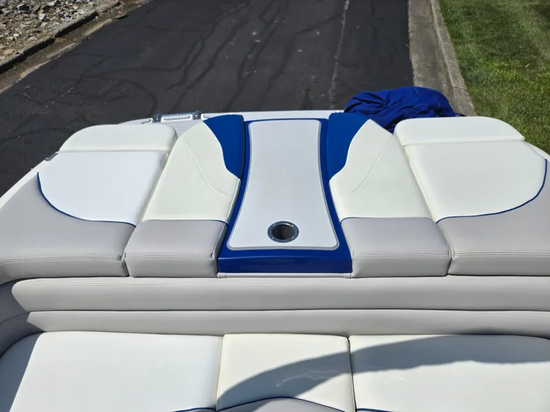Slide: The Image of 2013 Bryant 210 STE boat interior with white and blue cushioned seating. - 22