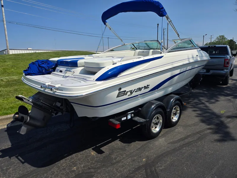 Slide: The Image of 2013 Bryant 210 STE boat on trailer, parked outdoors, with blue canopy and sleek design. - 3