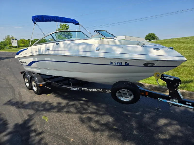 Slide: The Image of 2013 Bryant 210 STE boat on trailer with blue canopy, parked on sunny day. - 5