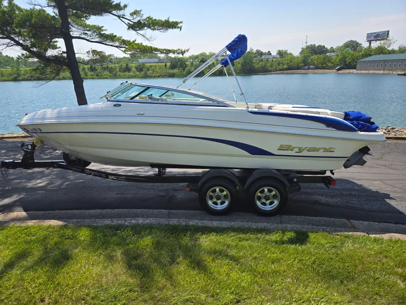 Slide: The Image of 2013 Bryant 210 STE boat on trailer by a lake, under clear skies. - 9
