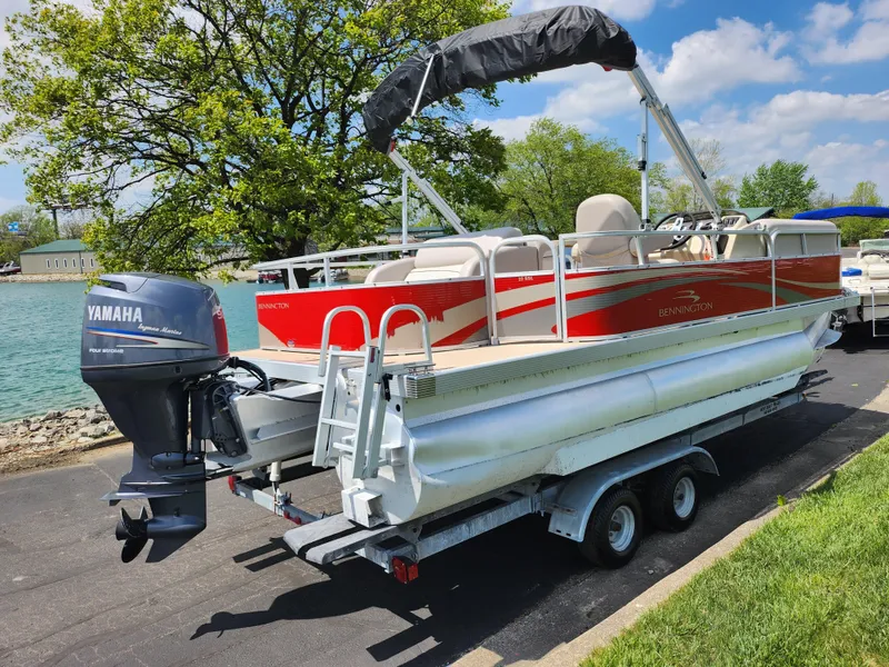 Slide: The Image of 2012 Bennington 22 SSL pontoon boat on trailer with Yamaha outboard motor, parked near water. - 1