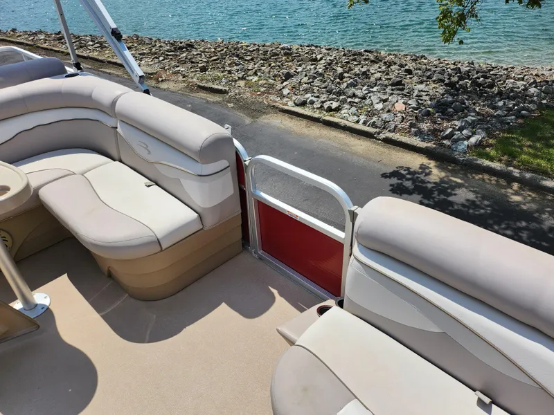 Slide: The Image of 2012 Bennington 22 SSL pontoon boat interior with beige seating by the water. - 12