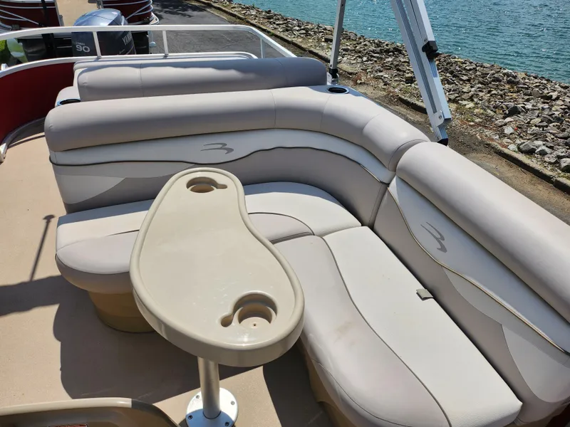 Slide: The Image of 2012 Bennington 22 SSL pontoon boat with beige seating and cup holders by the water. - 13