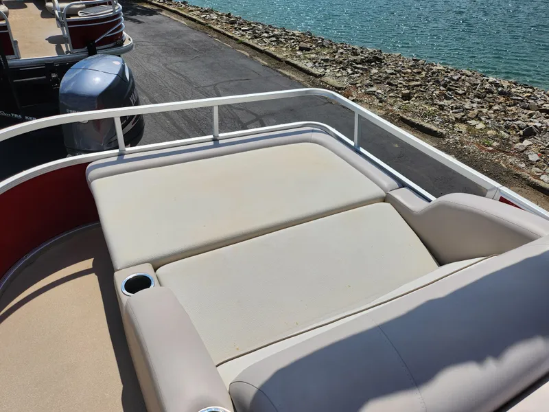Slide: The Image of 2012 Bennington 22 SSL boat with cushioned seating, near water and rocky shoreline. - 17